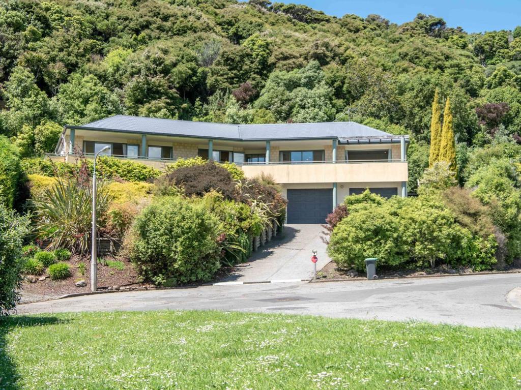 a house on the side of a hill with trees at Rue Noyer Lookout - Akaroa Holiday Home in Akaroa