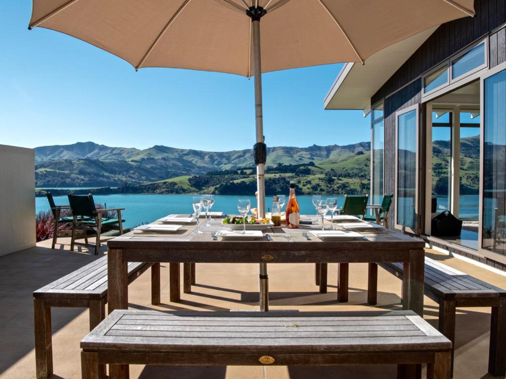 una mesa de madera con una sombrilla en el patio en Kotare Point Paradise - Akaroa Holiday Home en Akaroa