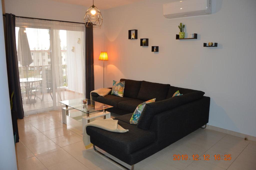 een woonkamer met een zwarte bank en een tafel bij Luxury Apartment in Paphos City