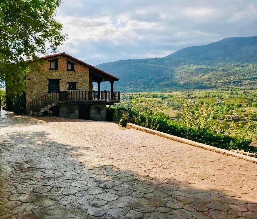 a house with a balcony and a stone driveway at La Seguirilla del Jerte in Casas del Castañar
