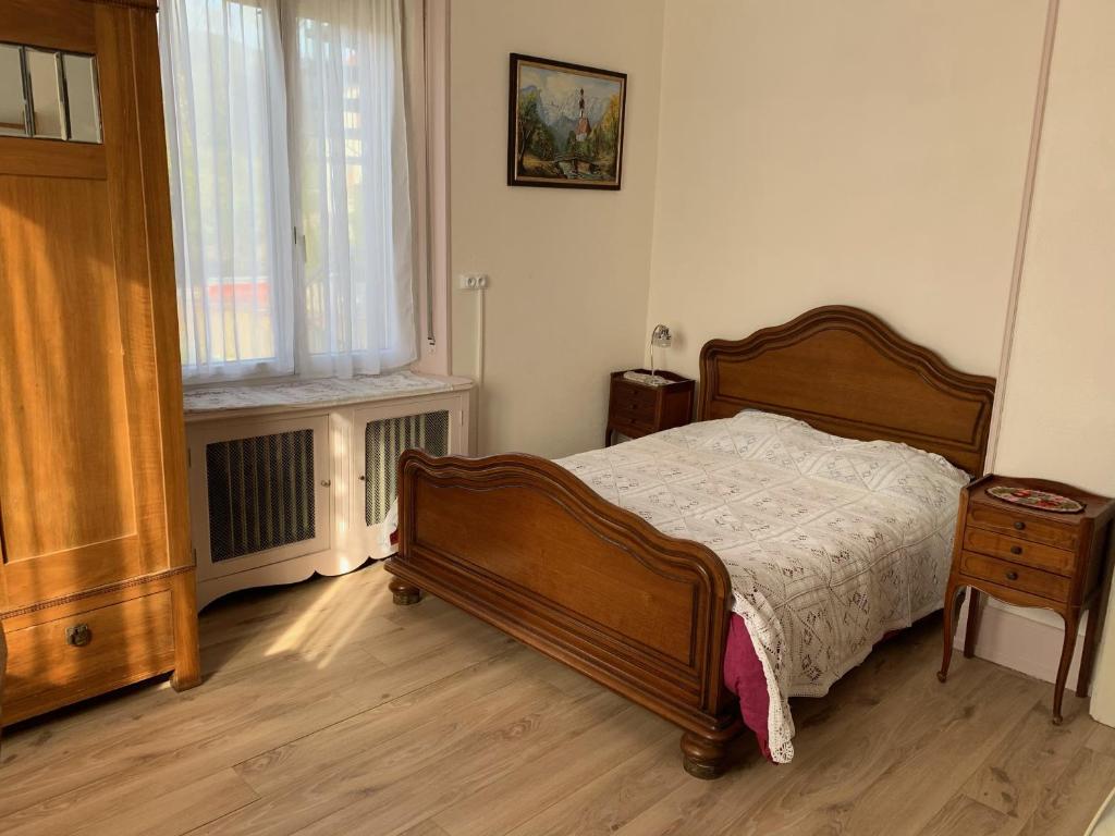a bedroom with a wooden bed and a window at Chambre Arnica lit 140 wifi sdb partagée in Saint-Amarin