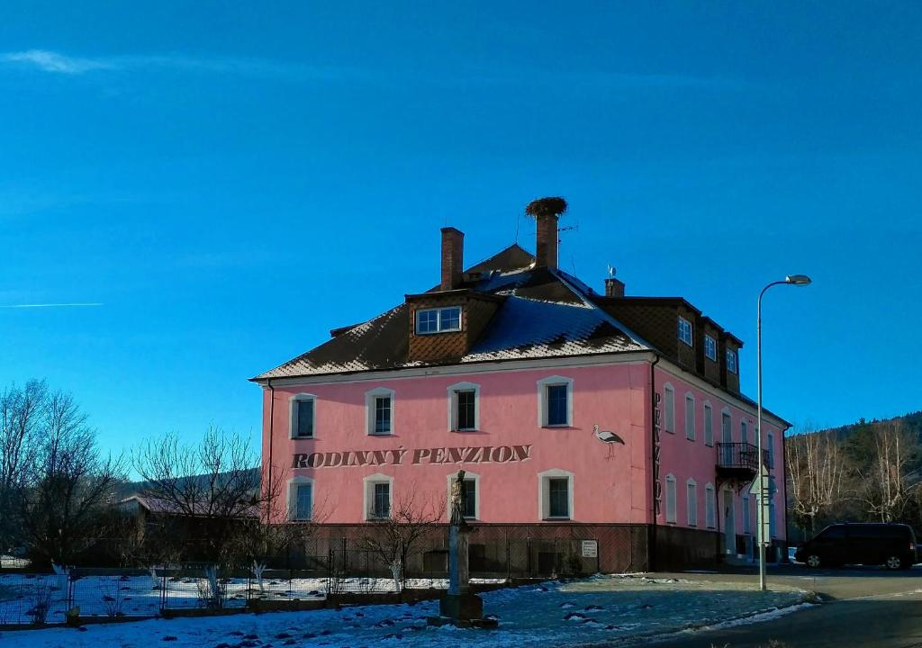 un viejo edificio rosa con un cartel. en Penzion Mlýnický Dvůr, en Červená Voda