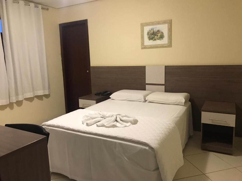 Un dormitorio con una cama con toallas blancas. en Hotel Moura, en Brumado