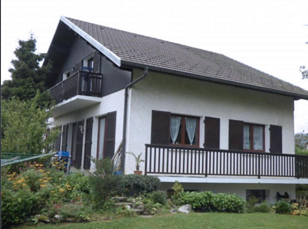 Biały dom z czarnymi oknami i balkonem w obiekcie Cosmic Latte w mieście Divonne-les-Bains