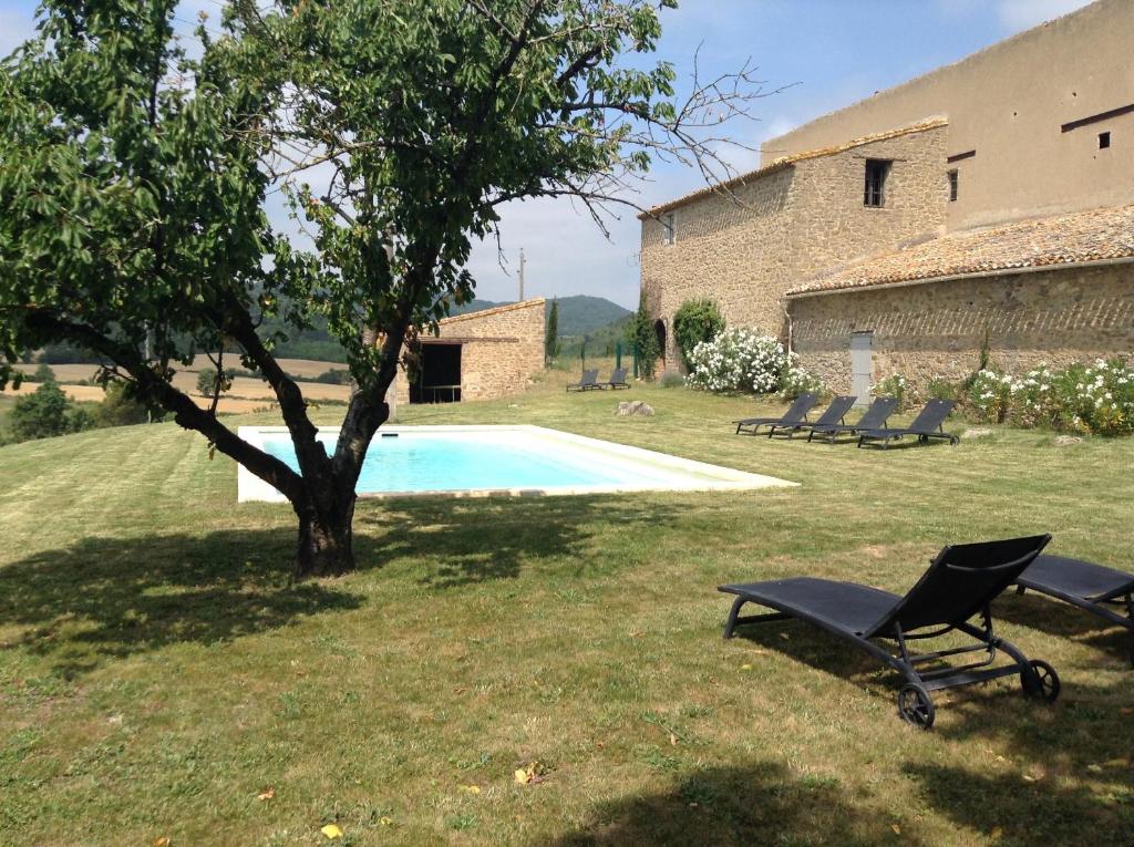 una piscina con una sedia e un albero accanto a un edificio di Maison vigneronne a Montlaur