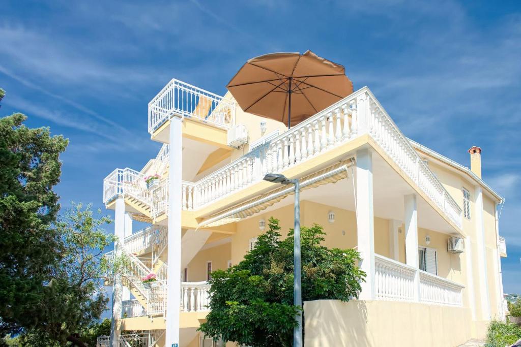 un grand bâtiment jaune avec un parapluie en haut dans l'établissement Apartments and rooms Gojko - 50 m from the beach, à Živogošće