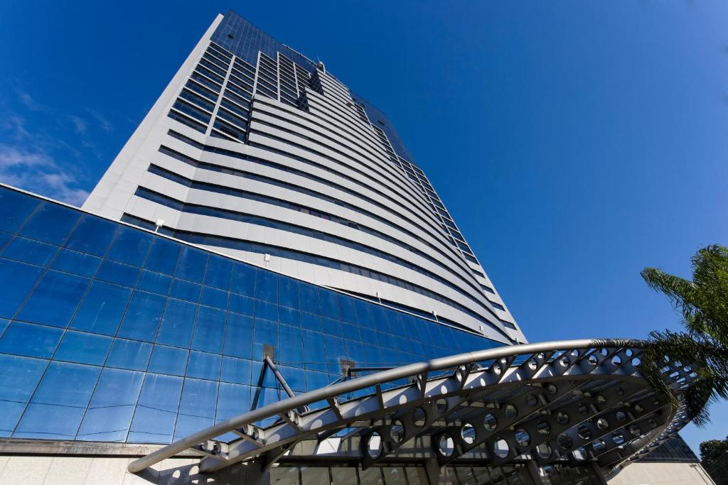 a tall glass building with a metal object in front of it at Intercity Salvador in Salvador