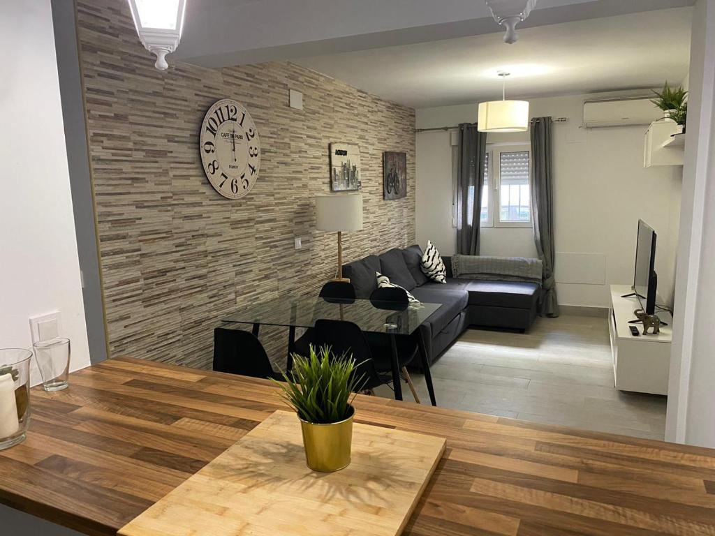 a living room with a couch and a clock on a brick wall at WISH SUITE NIEBLA DE SEVILLA in Seville