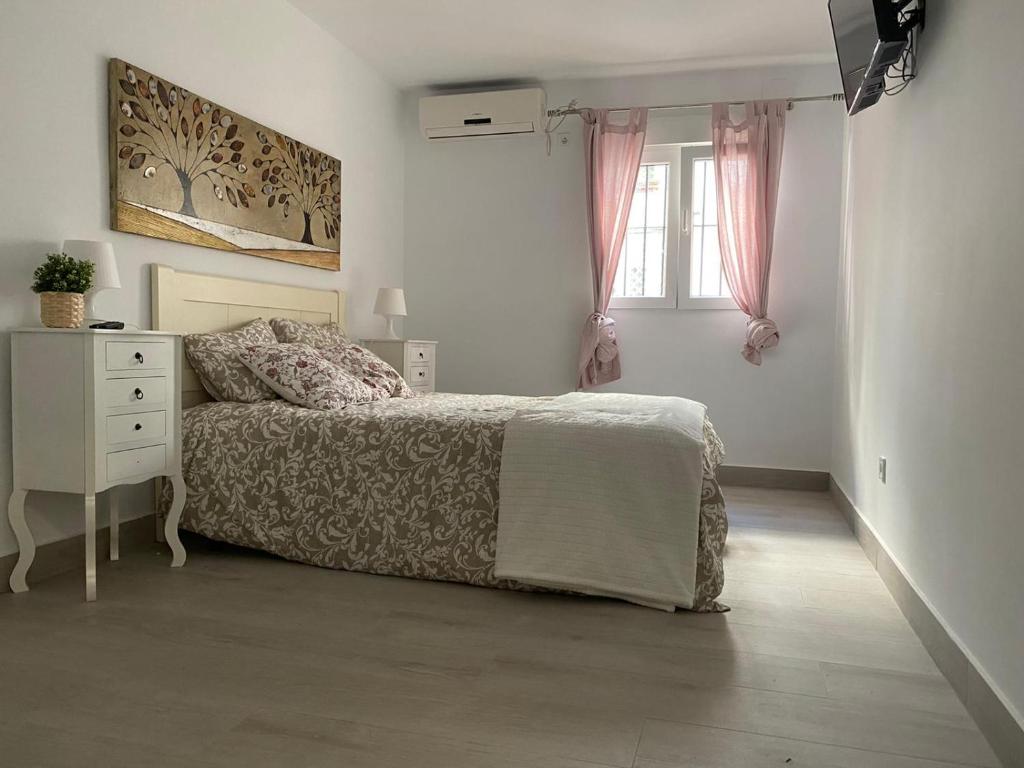 a bedroom with a bed and a dresser and a window at WISH SUITE NIEBLA DE SEVILLA in Seville