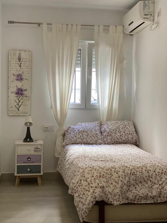 a bedroom with a bed and a dresser and a window at WISH SUITE NIEBLA DE SEVILLA in Seville