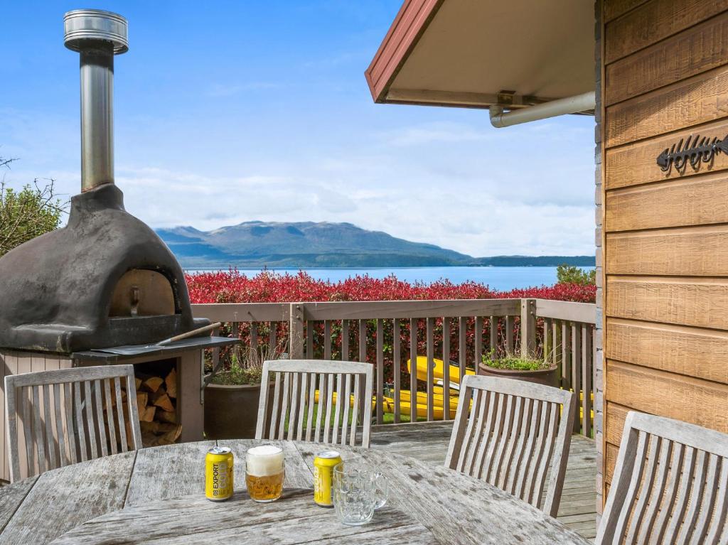 a table and chairs with a wood fired oven at Lakeside Escape - Lake Tarawera Holiday Home in Lake Tarawera