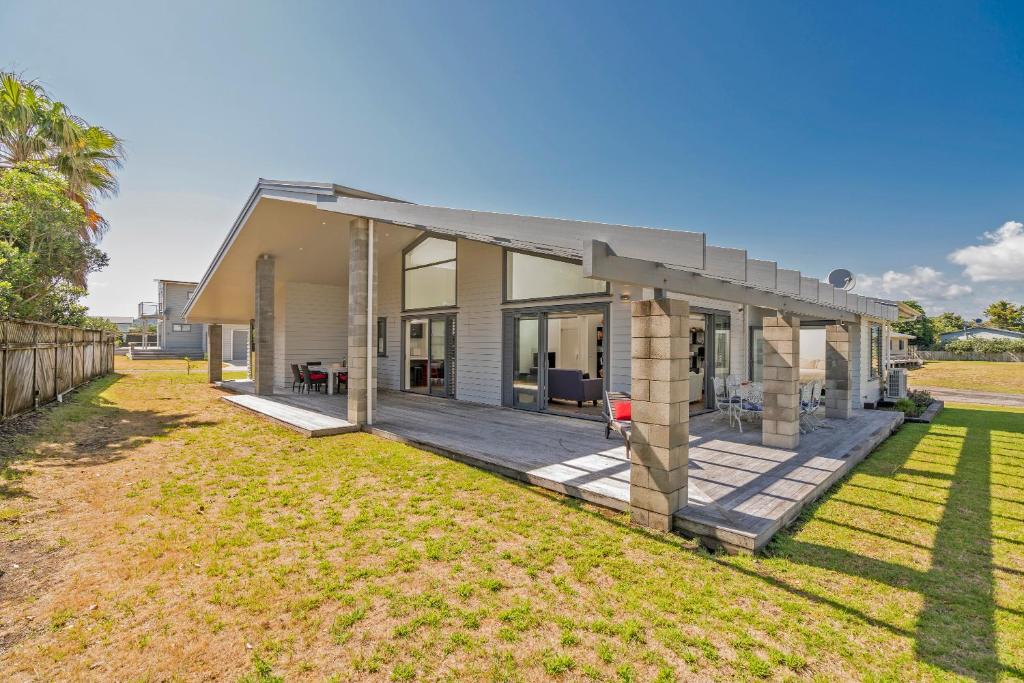 a house with a porch and a yard at Matarangi Marvel - Matarangi Holiday Home in Matarangi