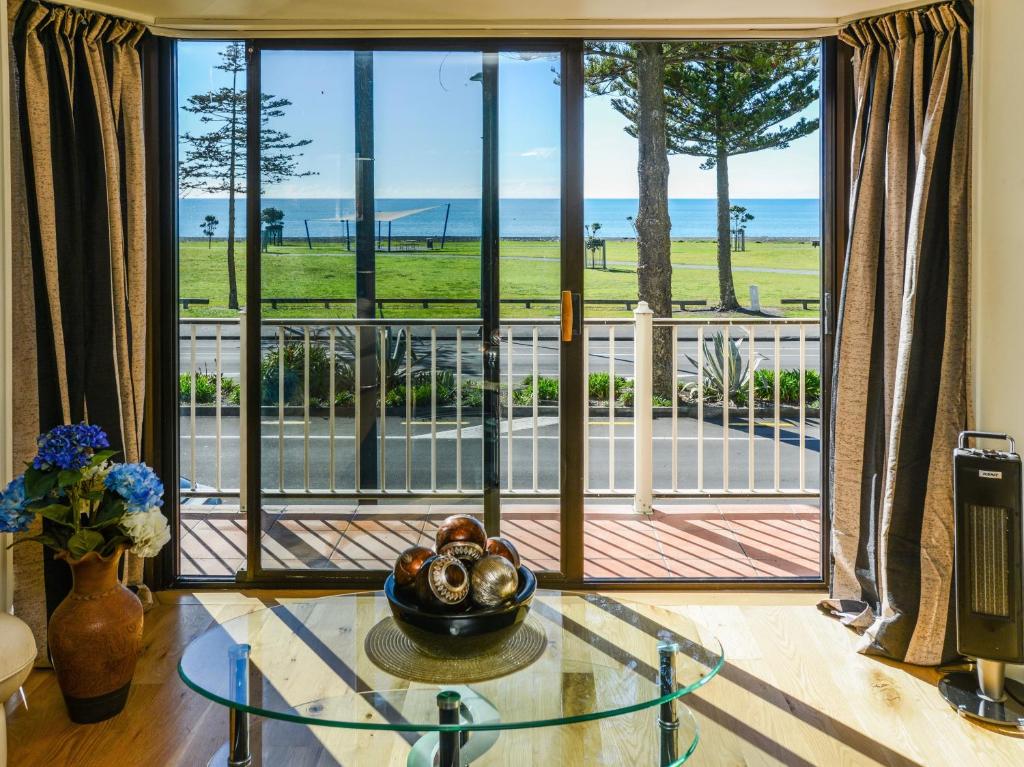 uma sala de estar com uma mesa de vidro e uma grande janela em Marine Parade Magic - Napier Holiday Home em Napier