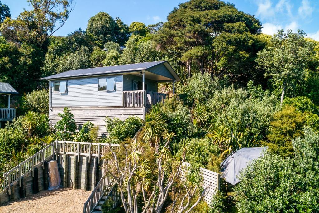 a house on the side of a hill with trees at Treetop Retreat - Onetangi Holiday Home in Onetangi