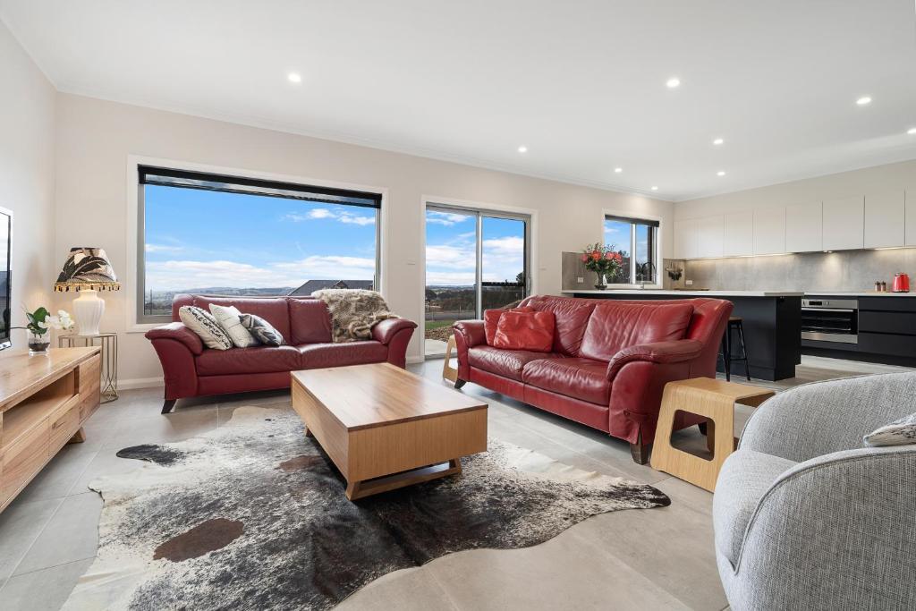 a living room with two red couches and a kitchen at Silverdown Luxury king rooms OR Apartment in Orange