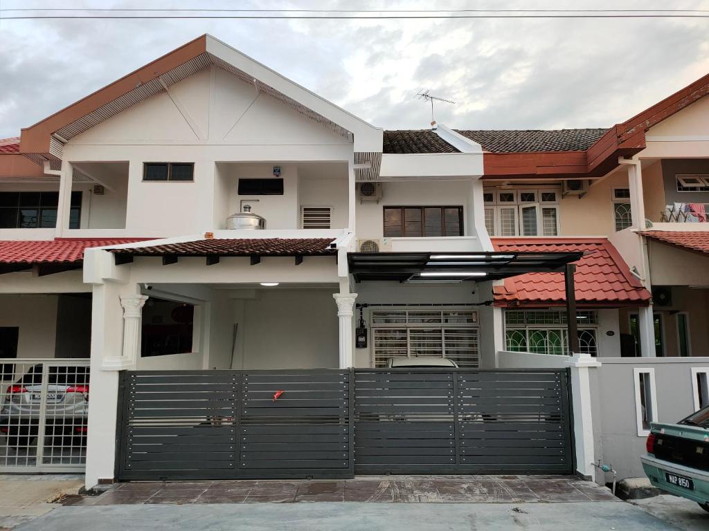 une maison blanche avec une porte de garage noire dans l'établissement 58 Kota Laksamana - Near Jonker Street for 10 to 15 Pax, à Malacca