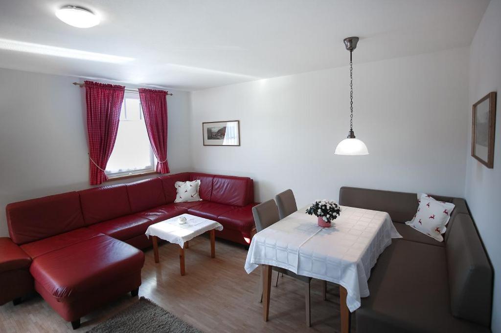 a living room with a red couch and a table at Appartements Ferienwohnungen Alpenblick in Faistenau