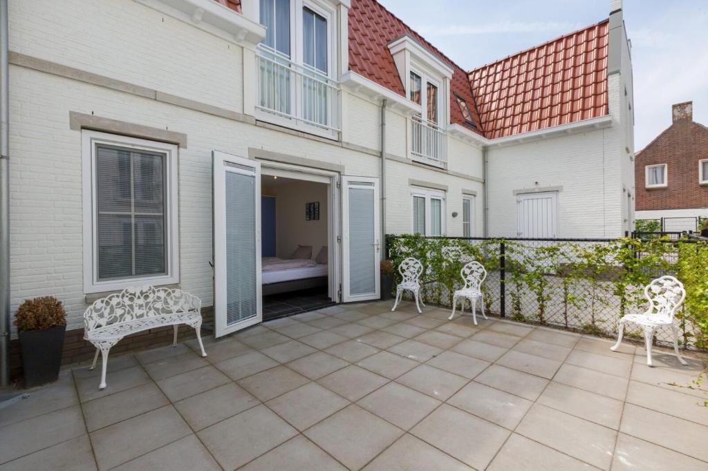 a patio with white chairs and a fence at Appartement - Kaapduinseweg 13 Dishoek 13H Luxe 6 personen in Koudekerke