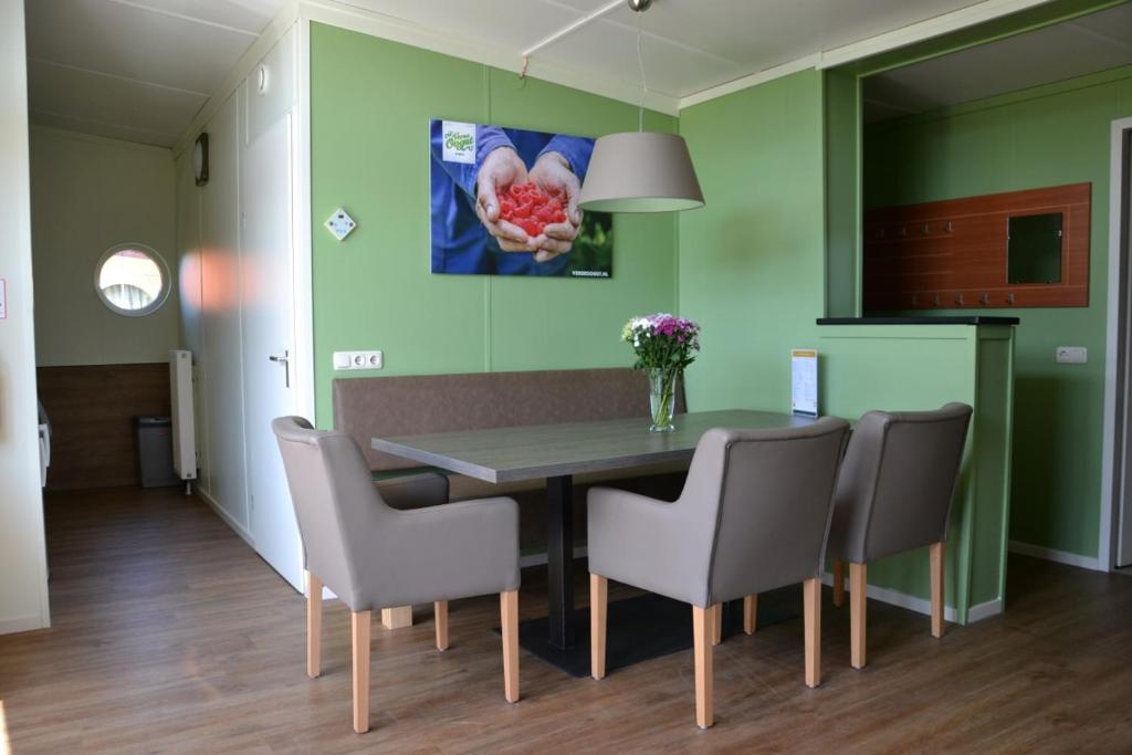 een eetkamer met groene muren en een tafel en stoelen bij Bungalow 14 personen in 's-Gravenzande
