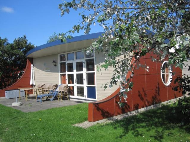 a building with a table and chairs in a yard at Bungalow 6 personen in 's-Gravenzande