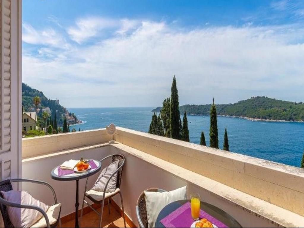 a balcony with a table and chairs and a view of the ocean at Villa Odak in Dubrovnik