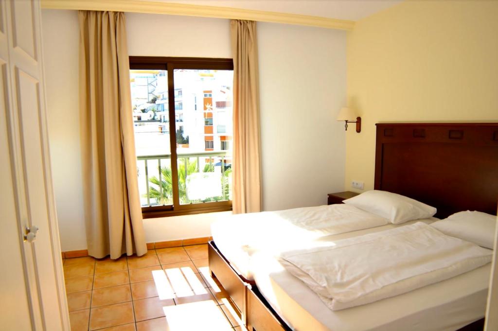 um quarto com uma cama e uma grande janela em Hapimag Ferienwohnungen Puerto de la Cruz em Puerto de la Cruz