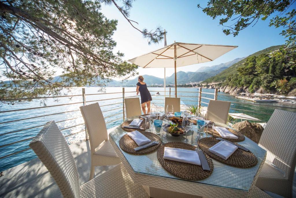 a table with chairs and an umbrella next to the water at Dukley Hotel & Resort in Budva
