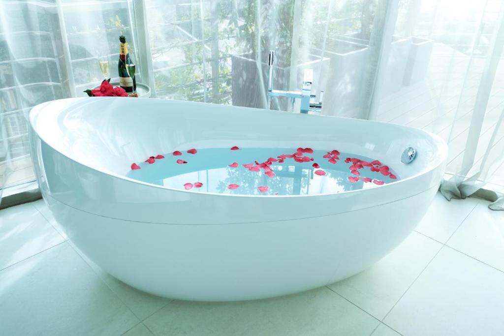 a white bath tub filled with red flowers in a bathroom at Dukley Hotel & Resort in Budva