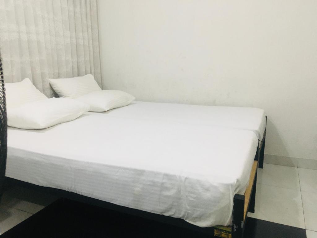 two beds in a room with white sheets and pillows at View City Point in Kandy