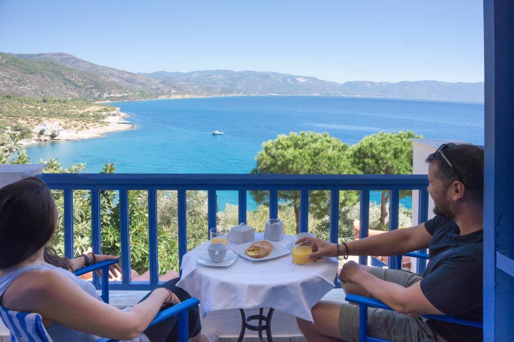 Un uomo e una donna seduti a un tavolo con un piatto di cibo di Sunrise Limnionas Apartments a Marathokampos