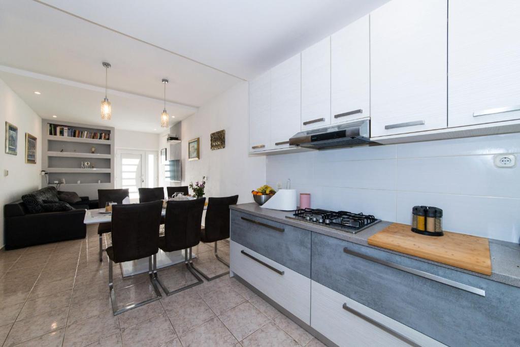 a kitchen with white cabinets and a table with chairs at Apartman LUKA Vila Vesa Promajna with jacuzzi & garden in Promajna