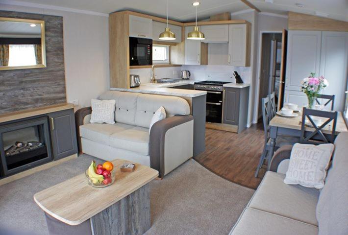 a living room with a couch and a table and a kitchen at The Royal Clovelly caravan with sea views in Bideford