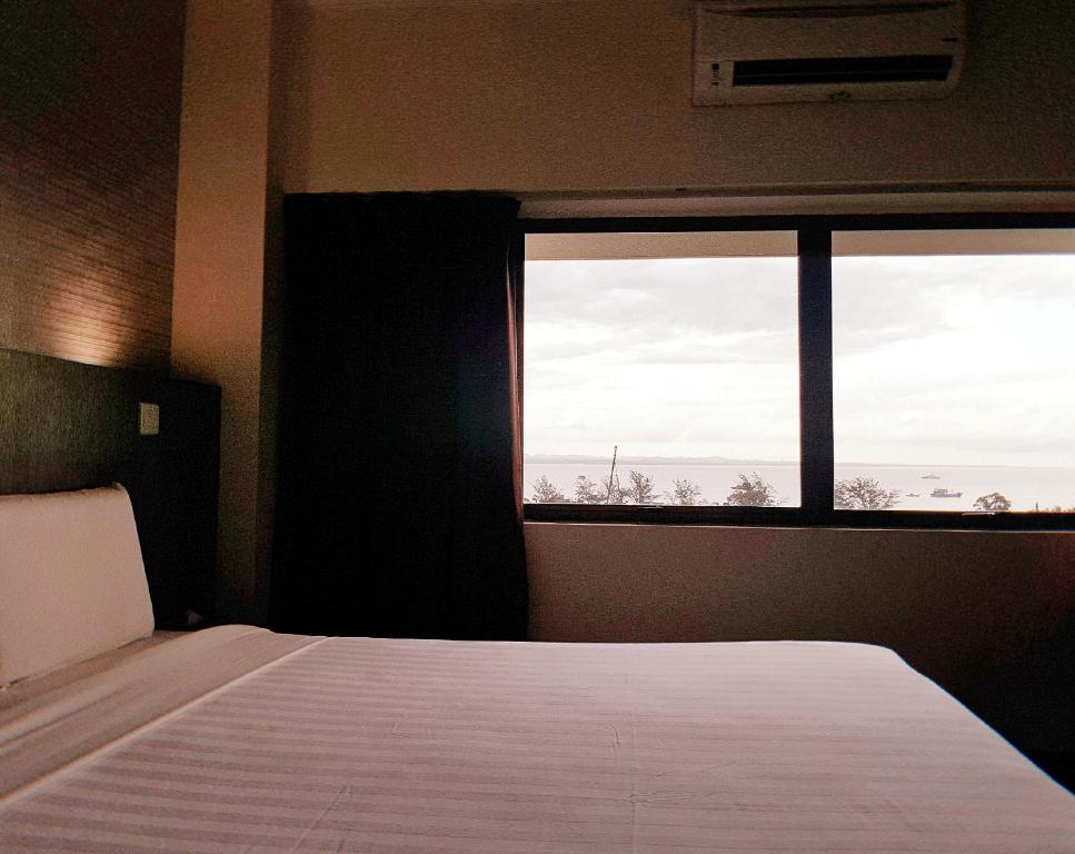 a bedroom with a bed and a large window at Check Inn Hotel Tawau in Tawau