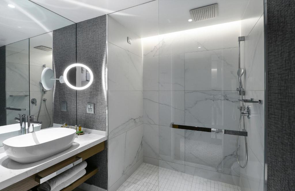 a white bathroom with a sink and a shower at Makedonia Palace in Thessaloniki