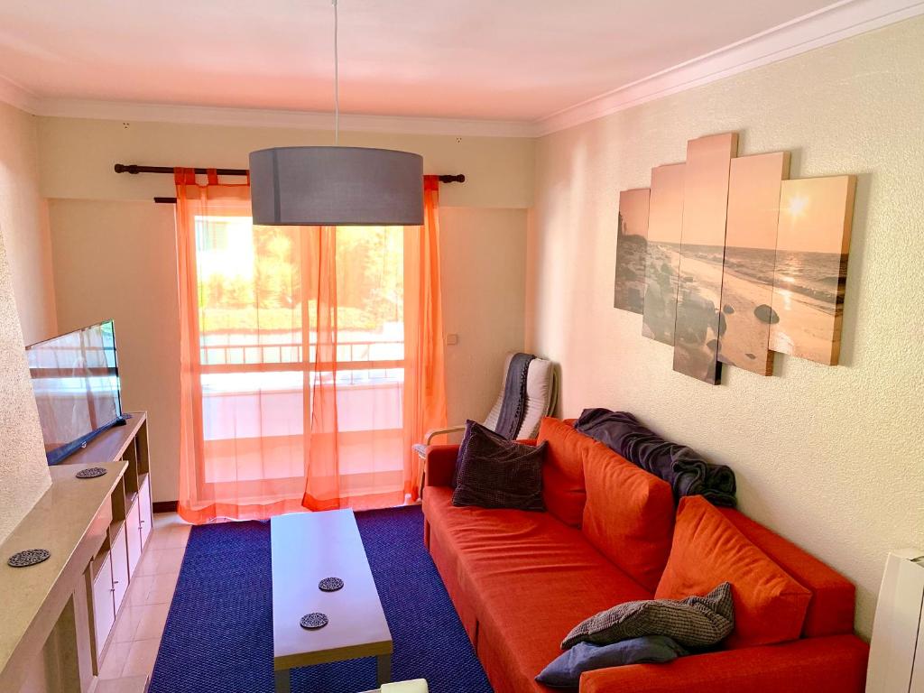 a living room with a red couch and a window at Cascais Spacious Getaway in Cascais