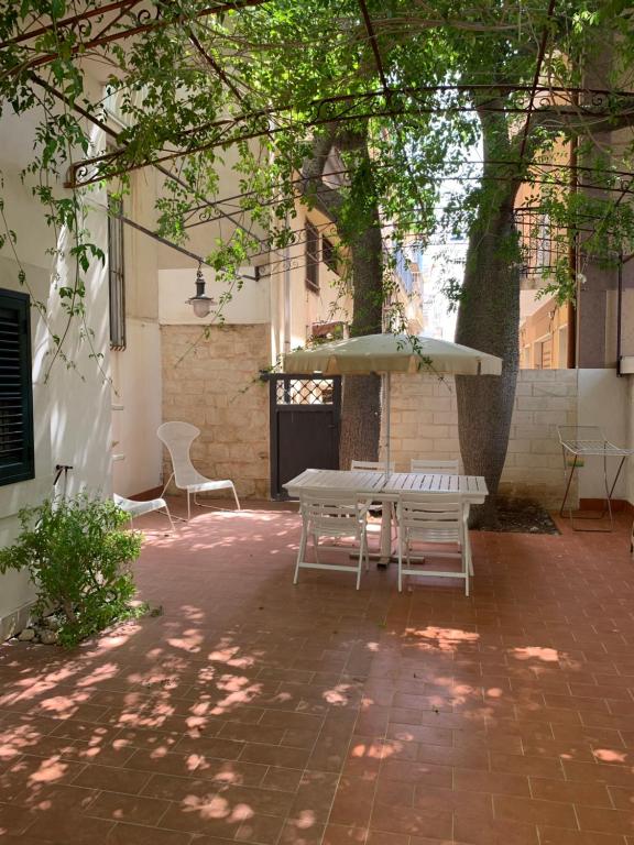 un patio con mesa y sillas bajo un árbol en Matteo's home, en Donnalucata