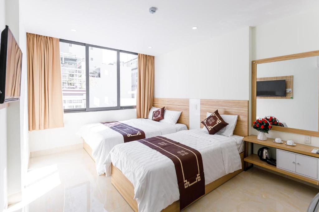 ein Hotelzimmer mit 2 Betten und einem TV in der Unterkunft Moschino HT in Nha Trang