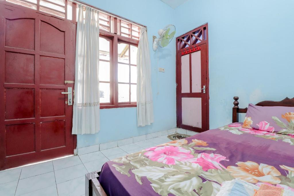 1 dormitorio con 1 cama y puerta abierta en Losmen Parikesit en Bantul