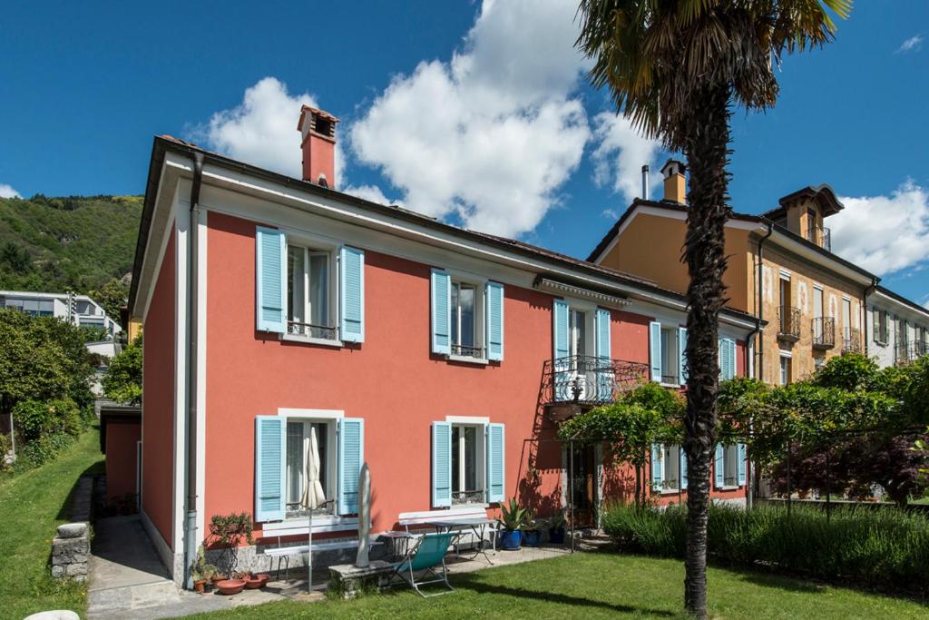 ロカルノにあるB&B villa sempreverdeのヤシの木が目の前に広がるピンクの家