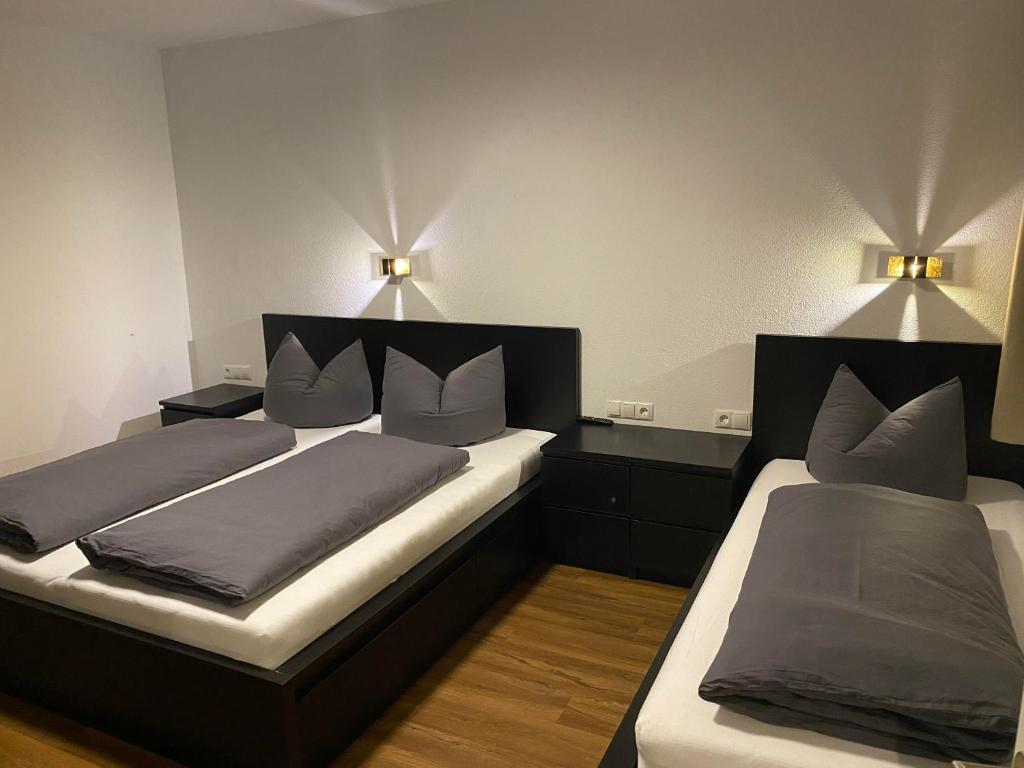 two beds in a room with two lamps on the wall at Kaiserblick Apartments in Oberau
