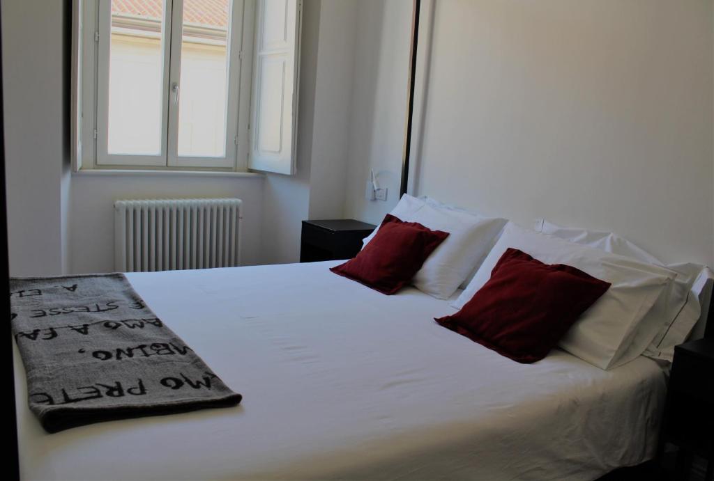 1 dormitorio con cama blanca y almohadas rojas en Palazzo della Torre Elegant Apartment in Como, en Como