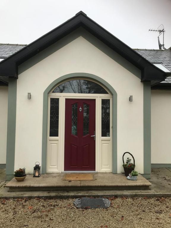een wit huis met een rode deur bij Laithreach Briuin B&B W23E0H9 in Maynooth