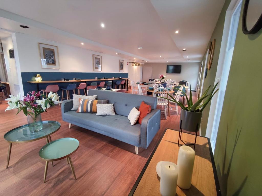 a living room with a blue couch and tables at Hôtel Le Lys in Oeting