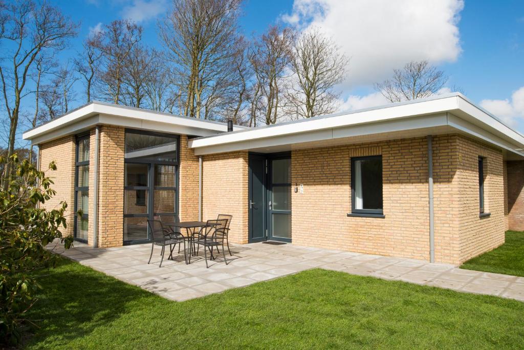 a brick house with a table and chairs on a patio at Vakantiewoning Hermelijn in Den Burg