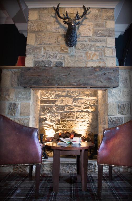 a stone fireplace with a table and two chairs at The Portland in Ashington