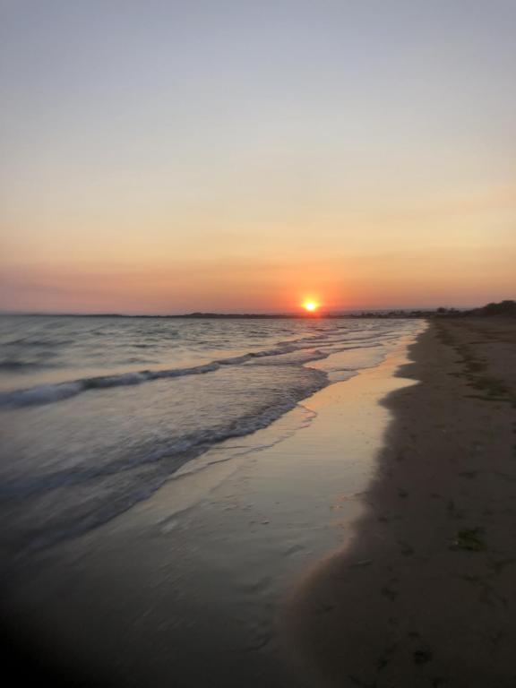 a sunset on a beach with the ocean at villa Lùmar fronte mare in Pachino