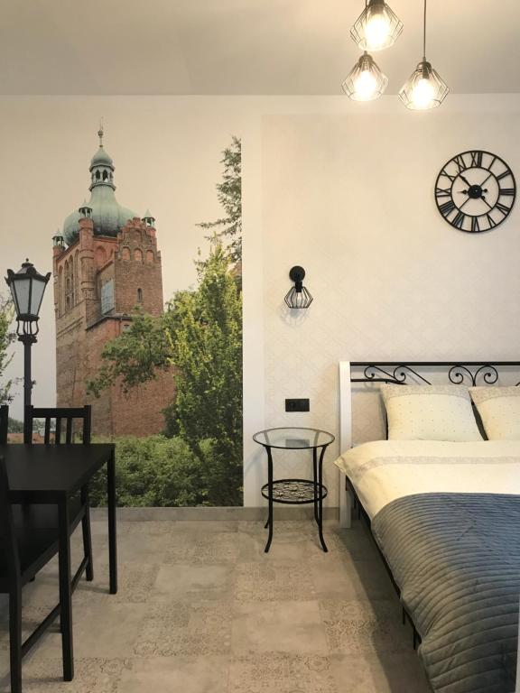 1 dormitorio con 1 cama y reloj en la pared en Płock by day, en Płock