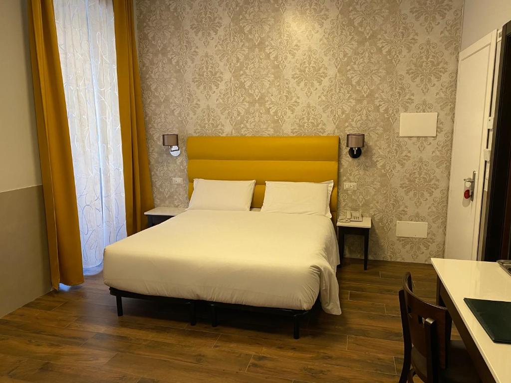 1 dormitorio con cama blanca y cabecero amarillo en Hotel Virgilio, en Roma