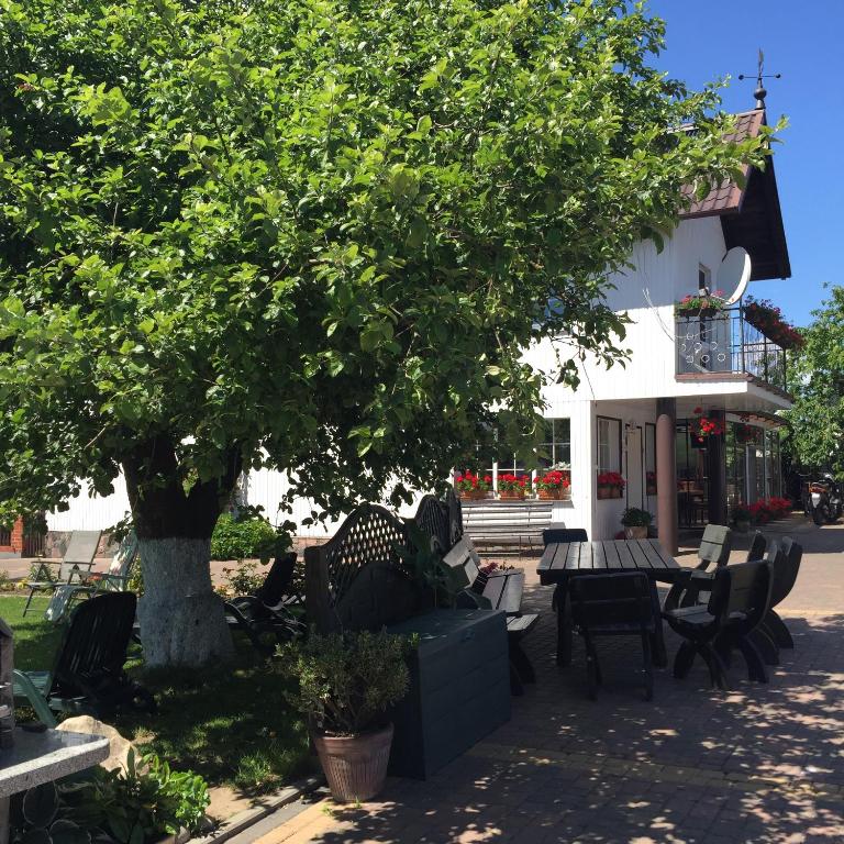 a table and chairs under a tree in front of a building at W Ciemno in Ciemno