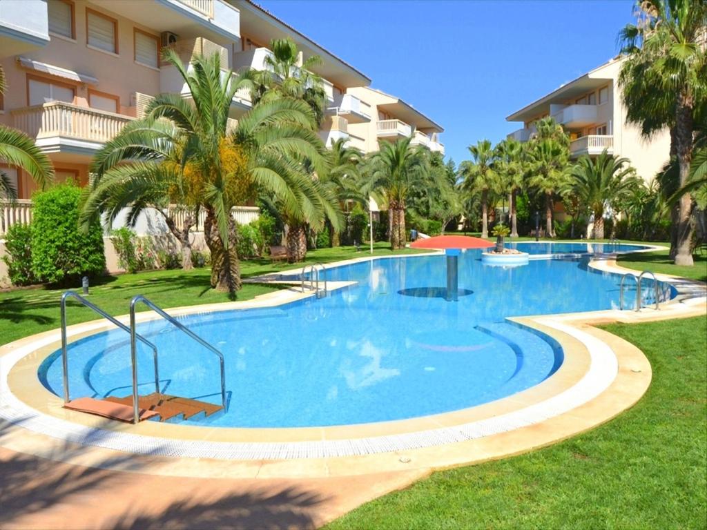 une grande piscine avec des palmiers en face d'un bâtiment dans l'établissement Apartamento Nou Fontana, à Jávea